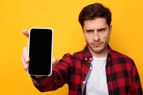 Грустный парень держит пустой экран смартфона — стоковое фото