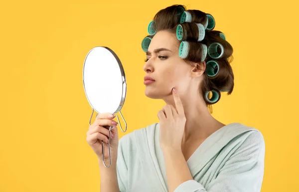 Lady Berührendes Gesicht mit Pickeln im Spiegel, gelber Hintergrund — Stockfoto
