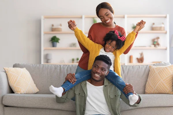 Huis Plezier. Vrolijke Afro-Amerikaanse familie van drie gerotzooi in de woonkamer — Stockfoto