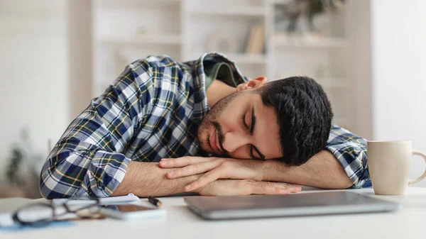 Uitgeput jonge man slapen op het werk zitten aan de balie — Stockfoto