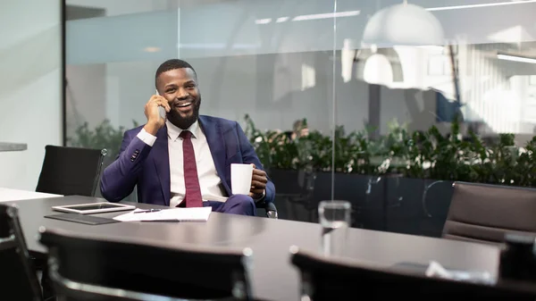 Negocio afroamericano positivo trabajando en la oficina, teniendo conversación telefónica — Foto de Stock