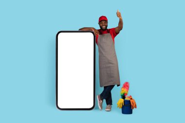 Siyah Temizlikçi Büyük Boş Akıllı Telefonun yanında duruyor ve Başparmağını kaldırıyor