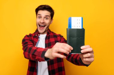 Bilet ve pasaport gösteren heyecanlı genç adam.