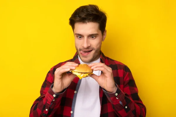 Engraçado jovem cara segurando hambúrguer no estúdio — Fotografia de Stock
