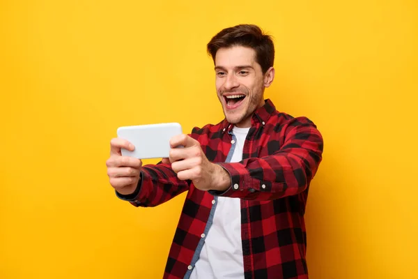 Lelaki bersemangat bermain game mobile dengan latar belakang kuning — Stok Foto
