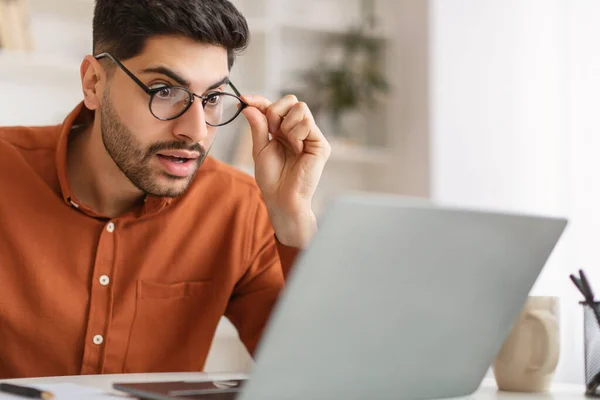 Schockierter Araber benutzt Laptop und schaut auf Bildschirm — Stockfoto