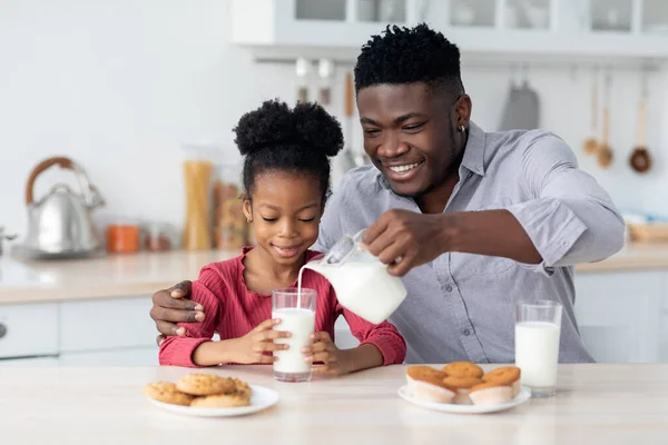 Milující černošky otec nalévání mléka pro jeho roztomilé dcerušky — Stock fotografie