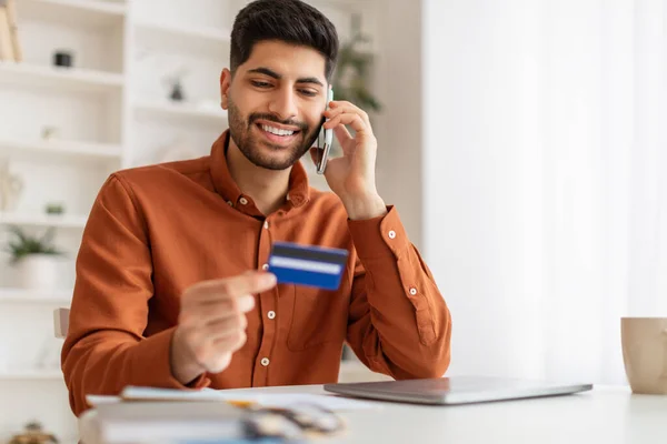 Sonriente hombre usando tarjeta de crédito hablando en el teléfono inteligente — Foto de Stock