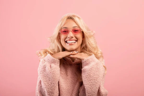 Glada söt dam lutar haka på händer och ler mot kameran, poserar över rosa studio bakgrund — Stockfoto