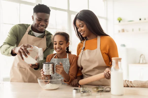 Zwarte ouders en dochter toevoegen bloem bakken koekjes in de keuken — Stockfoto