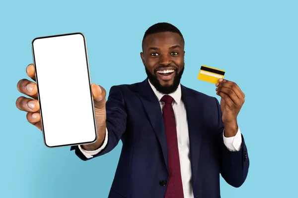 Płatności online. Szczęśliwy czarny biznesmen z pustym smartfonem i kartą kredytową — Zdjęcie stockowe