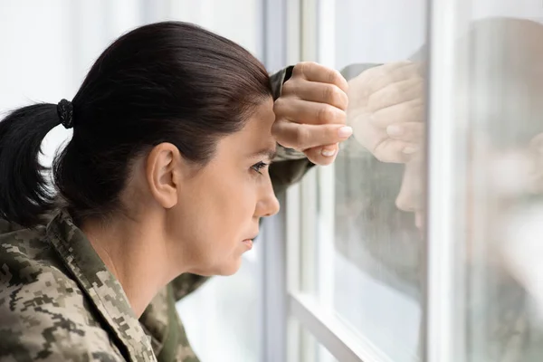 Concepto de Depresión. Mujer pensativa en uniforme militar mirando por la ventana — Foto de Stock