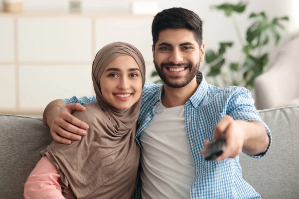 Glückliches Paar aus dem Nahen Osten, das zu Hause fernsieht und die Kanäle umschaltet — Stockfoto