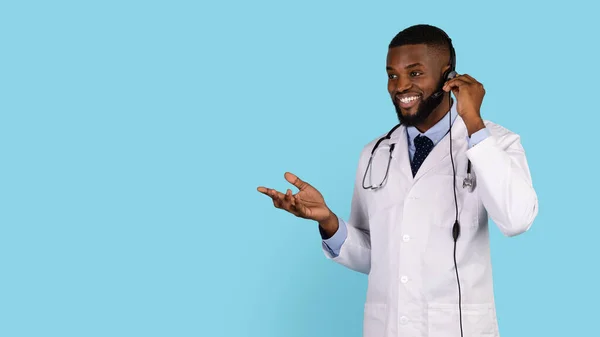 网上咨询。面带微笑的黑人医生头戴耳机与病人交谈 — 图库照片