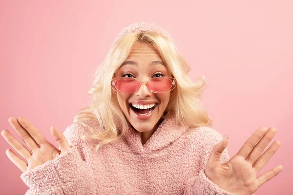 Överraskad ung kvinna med öppen mun, poserar över rosa studio bakgrund och tittar på kameran i spänning — Stockfoto