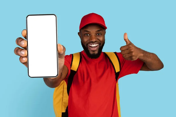 Замовте тут. Щасливий чорний хлопець доставки з термо рюкзаком Holding порожній смартфон — стокове фото