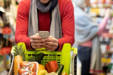 Süpermarkette alışveriş yaparken cep telefonu kullanan tanınmayan bir adam