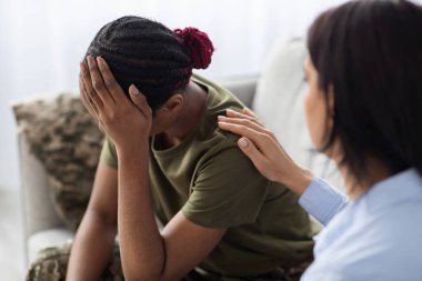 Psychotherapist lady consoling and supporting black female soldier with ptsd, closeup shot clipart