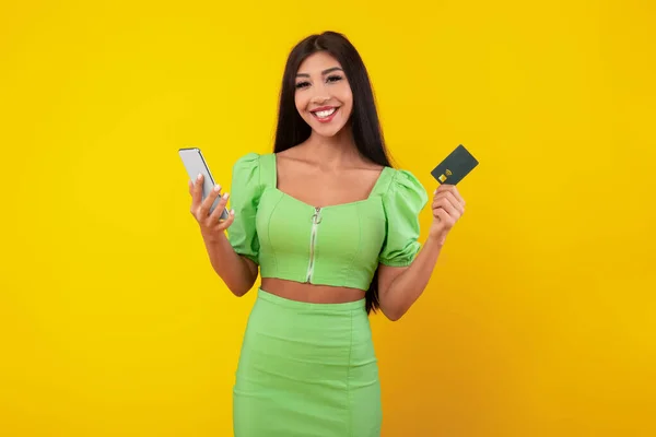 Spännande ung kvinna med kreditkort och mobiltelefon — Stockfoto