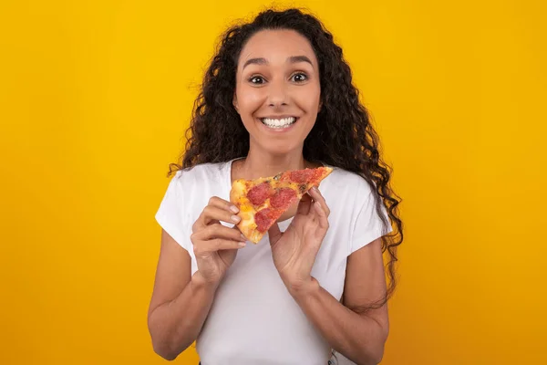 Happy Latin Lady Holding Pizza slice in de studio — Stockfoto