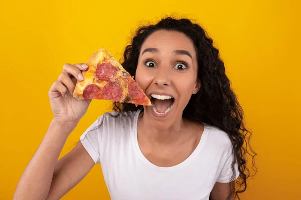 Happy Latin Lady Holding Pizza slice in de studio — Stockfoto