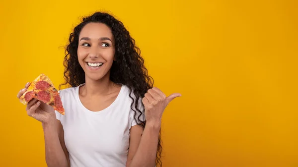 Portret van een gelukkige dame die pizza vasthoudt en wegwijst. — Stockfoto