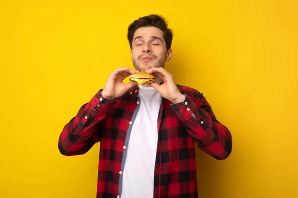 Primer plano de chico emocionado comiendo sabrosa hamburguesa en el estudio — Foto de Stock