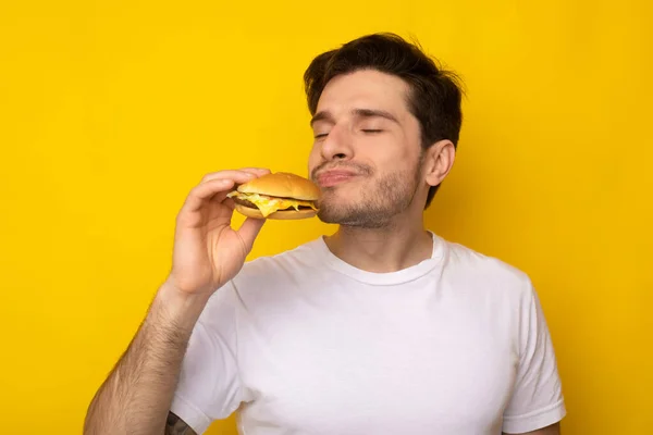 Primo piano di eccitati ragazzo mangiare gustoso hamburger a studio — Foto Stock