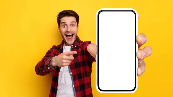 Шокированный парень указывает на белый пустой экран смартфона — стоковое фото