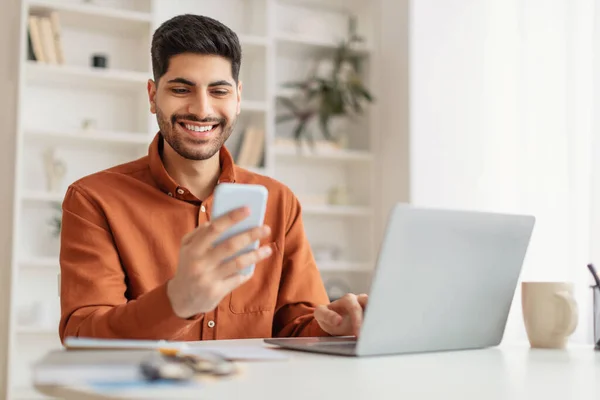 Retrato de homem sorridente usando smartphone e pc em casa — Fotografia de Stock