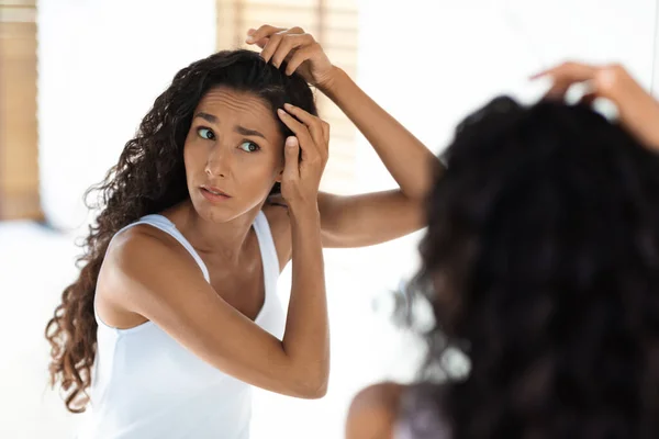 Mujer joven preocupada revisando sus raíces del pelo en casa, teniendo problema de caspa —  Fotos de Stock