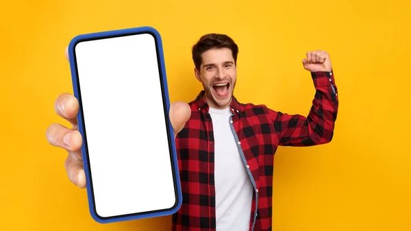 Веселый парень показывает пустой экран смартфона жестом да — стоковое фото