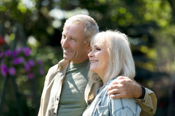 Glada äldre makar omfamnar och njuter av varma vårdagar, umgås utomhus — Stockfoto