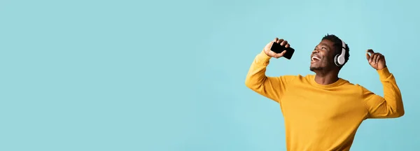 Tipo negro emocional cantando karaoke, usando el teléfono celular — Foto de Stock