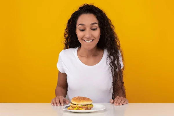 Engraçado latina senhora olhando para hambúrguer no estúdio — Fotografia de Stock