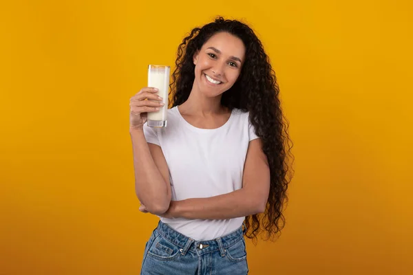 Gelukkig jong vrouw holding glas met melk in studio — Stockfoto
