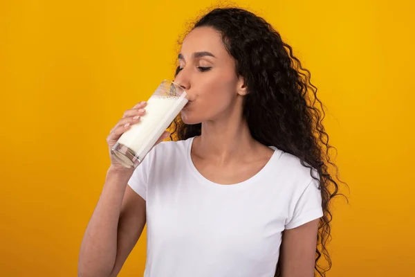 Jovem mulher bebendo leite de vidro no estúdio — Fotografia de Stock