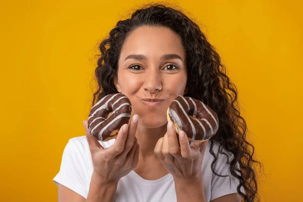 Engraçado latina senhora segurando mastigar donut bolo no estúdio — Fotografia de Stock