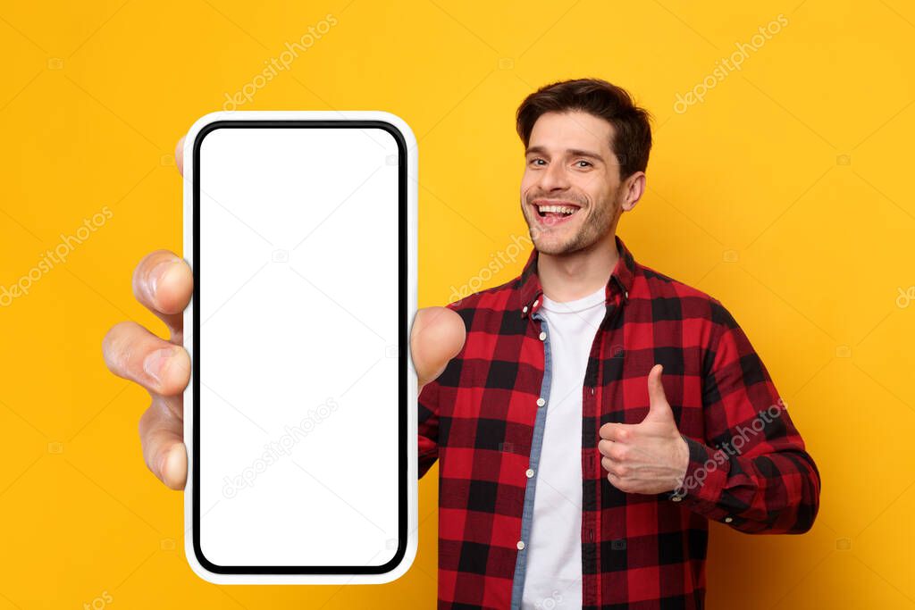 Cheerful guy showing big white empty smartphone screen and like