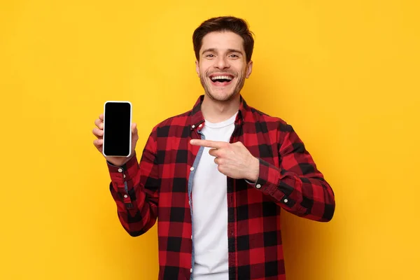 Cara alegre apontando para a tela do telefone inteligente vazio — Fotografia de Stock