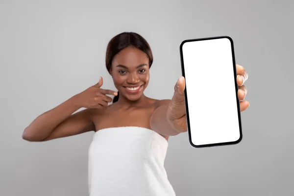 Hermosa joven mujer negra envuelta en toalla de baño Demostración de Big Blank Smartphone —  Fotos de Stock