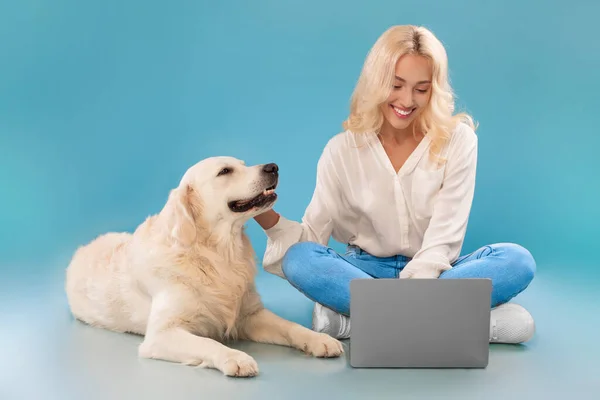 幸せな犬と床に座ってラップトップを使用して若い女性 — ストック写真