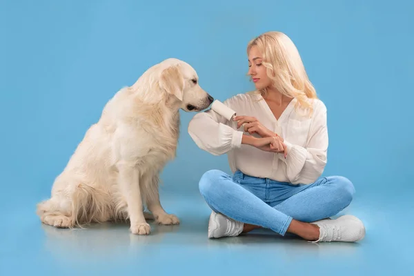 Donna che pulisce i suoi vestiti da pelliccia di cane con rullo adesivo — Foto Stock