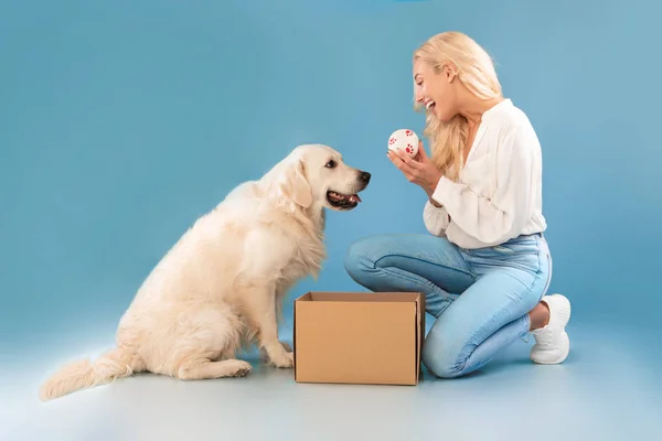 Opgewonden jonge vrouw spelen met hond holding bal — Stockfoto