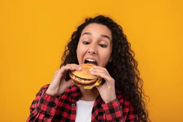 Funny latina dama celebración hamburguesa mordiendo sándwich en el estudio — Foto de Stock