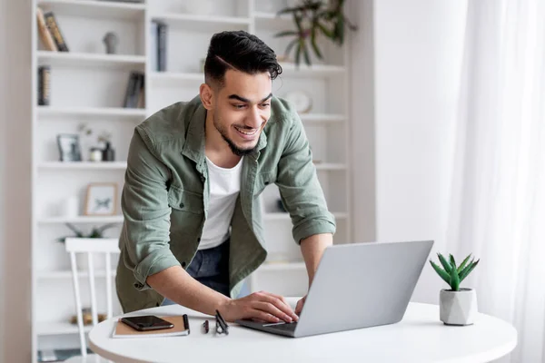 Mosolygós jóképű arab férfi használja Laptop otthon Office, Álló közel íróasztal — Stock Fotó