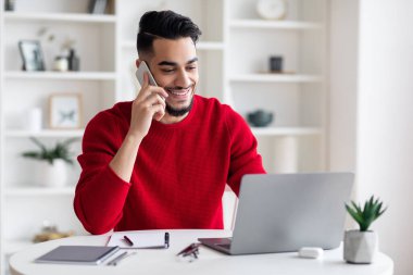 İçişleri Bakanlığı 'nda laptopta çalışırken Arap adam cep telefonuyla konuşuyor.