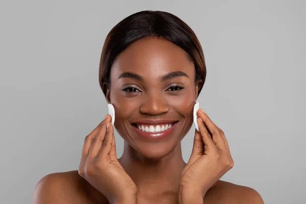 Cuidado com a pele. Cara de limpeza feminina afro-americana bonita feliz com duas almofadas de algodão — Fotografia de Stock