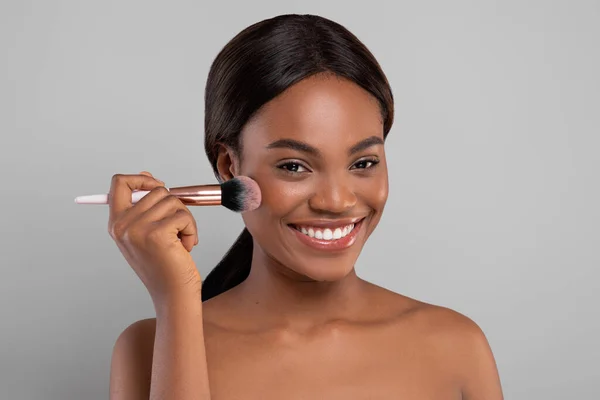Närbild Porträtt av attraktiv glad svart kvinna med hjälp av Blusher Brush — Stockfoto