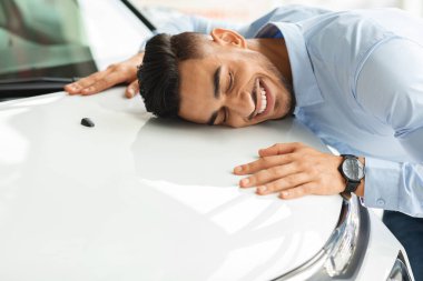 Mutlu genç Arap adam rüyalarının arabasını kucaklıyor.